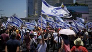 Demonstranten schwenken auf einer Straße in Tel Aviv israelische Flaggen. © dpa-Bildfunk/AP Foto: Leo Correa