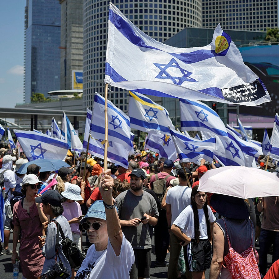 Demonstranten schwenken auf einer Straße in Tel Aviv israelische Flaggen. © dpa-Bildfunk/AP Foto: Leo Correa