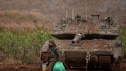 Ein israelischer Soldat geht an einem Panzer in der Nähe der israelisch-libanesischen Grenze vorbei, gesehen von Nordisrael aus. © picture alliance/dpa/AP | Leo Correa Foto: Leo Correa