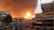 Rauch und Flammen steigen hinter Gebäuden im Jemen auf. © AP Foto: Uncredited