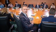 Finanzminister Christian Lindner (FDP) sitzt mit weiteren Kabinettsmitgliedern in Berlin vor Beginn einer Sitzung an einem großen Tisch. © dpa bildfunk Foto: Michael Kappeler