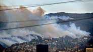 Rauch ist zu sehen bei Flächenbränden entlang eines Hügels im Stadtteil Brentwood von Los Angeles. Foto: © dpa-Bildfunk/AP Foto: Richard Vogel