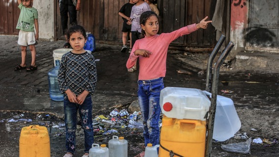 Palästinensische Kinder auf einer Straße in Rafah stehen mit Kanistern für Wasser an. © dpa Foto: Abed Rahim Khatib