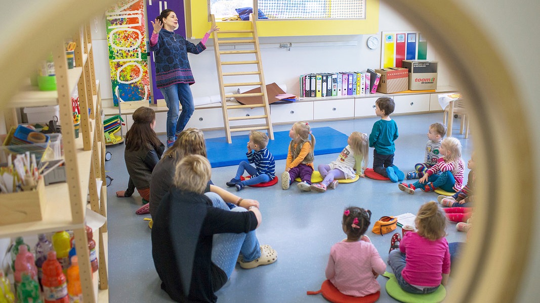 In einer bilingualen Kita in Schwerin agiert eine Erzieherin mit Kindern in einem Sitzkreis.