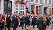 Dänemarks Königin Mary (M) und König Frederick X. (r) laufen durch eine Straße in Flensburg. © dpa-Bildfunk Foto: Frank Molter