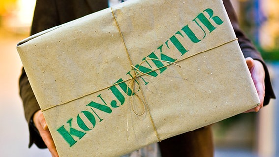 Ein Mann hält ein Paket mit der Aufschrift "Konjunktur" in den Händen © dpa Bildfunk Foto: Patrick Pleul