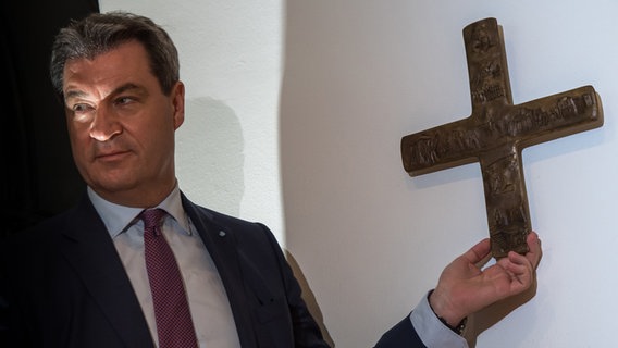 Markus Söder (CSU) hängt ein Kreuz im Eingangsbereich der bayerischen Staatskanzlei auf. © dpa Bildfunk Foto: Peter Kneffel