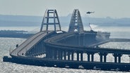 Ein Brand auf der Krim-Brücke von Kertsch, die eine Verbindung zwischen Russland und der Schwarzmeer-Halbinsel Krim herstellt, wird aus der Luft gelöscht. © Uncredited/AP/dpa 