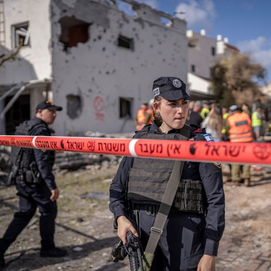 Sicherheitskräfte stehen vor beschädigten Gebäuden nach einem angeblichen Angriff der pro-iranischen Hisbollah-Bewegung. © picture alliance/dpa Foto:  Ilia Yefimovich