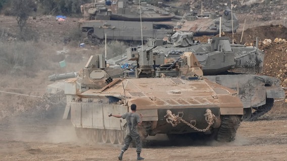 Israelische gepanzerte Mannschaftstransportwagen und Panzer manövrieren in einem Bereitstellungsraum im Norden Israels nahe der israelisch-libanesischen Grenze. © Baz Ratner/AP/dpa 