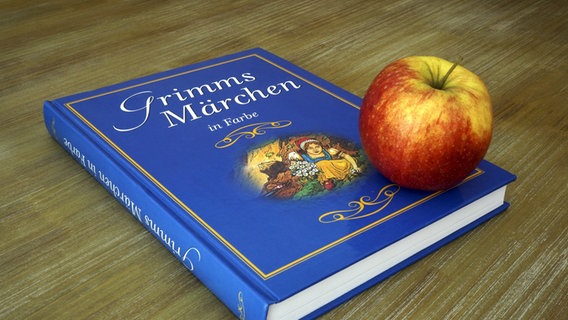 Ein Apfel liegt auf einem blauen Märchenbuch mit dem Namen "Grimms Märchen in Farbe". © picture alliance/ZB Foto: Sascha Steinach