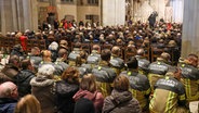 Einsatzkräfte der Feuerwehr sitzen in einer Gedenkveranstaltung im Magdeburger Dom. Am Vorabend war ein Autofahrer auf dem Magdeburger Weihnachtsmarkt in eine Menschengruppe gefahren. © Jan Woitas/dpa 