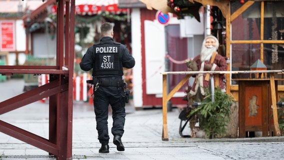 Ein Polizist geht über den gesperrten Weihnachtsmarkt in Magdeburg. © dpa Foto: Sebastian Kahnert