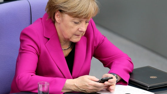 Angela Merkel (CDU) schaut während einer Sitzung im Deutschen Bundestag auf ihr Mobiltelefon. © picture alliance / dpa Foto: Wolfgang Kumm