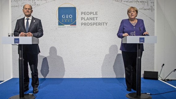 Bundesfinanzminister Olaf Scholz und Bundeskanzlerin Merkel bei einer Pressekonferenz auf dem G20-Gipfel in Rom. © dpa Foto: Oliver Weiken