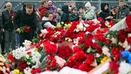 Menschen legen Blumen und Spielzeug am Zaun neben dem Konzertsaal bei Moskau ab, auf den am 22. März 2024 ein Terroranschlag verübt worden war. © Vitaly Smolnikov/AP/dpa 