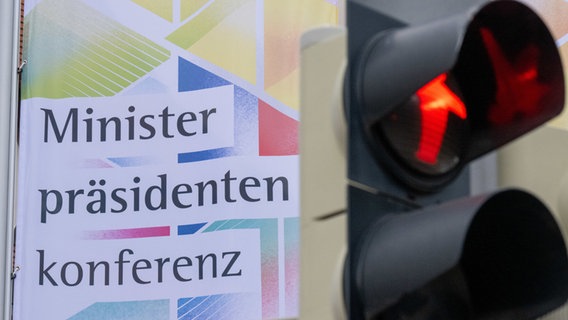 Eine Fußgängerampel zeigt rot, dahinter weht eine Flagge der Ministerpräsidentenkonferenz © Hendrik Schmidt/dpa Foto: Hendrik Schmidt