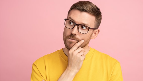 Ein Mann mit Brille vor rosabarbenen Hintergrund denkt nach (Themenbild) © picture alliance / Zoonar Foto: Dmitrii Marchenko