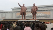 In Pjöngjang stehen Menschen vor den Statuen der ehemaligen Führer Kim Il Sung und Kim Jong Il. © Cha Song Ho/AP/dpa 