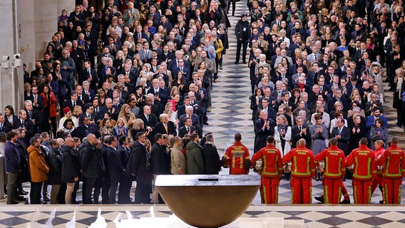 Feuerwehrleute, Retter und Bauarbeiter, die an der Restaurierung beteiligt waren, bei der Wiedereröffnung in der Kathedrale Notre-Dame in Paris. © dpa bildfunk/AP/POOL AFP/AP Foto: Ludovic Marin