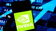 Das Logo des US-Chipherstellers NVIDIA auf einem Smartphone-Display vor einer Börsenanzeige © picture alliance Foto: Sipa USA | SOPA Images