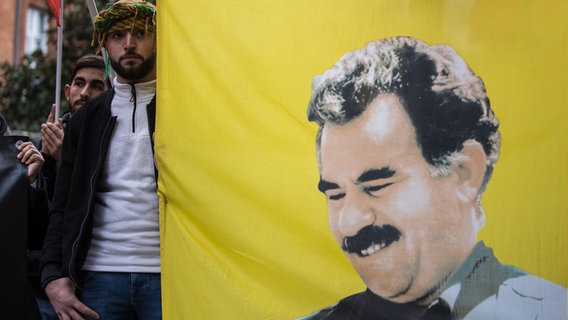 Anhänger der PKK halten ein Banner mit dem Porträtbild von Abdullah Öcalan. © picture alliance / Hans Lucas | Frederic Scheiber 