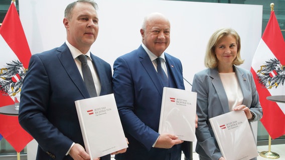 Die österreichischen Parteivorsitzenden Christian Stocker von der ÖVP, Andreas Babler von der SPÖ und Beate Meinl-Reisinger von den NEOS posieren mit ihrem Regierungsprogramm nach einer Pressekonferenz zur Bildung einer Koalitionsregierung. © dpa-Bildfunk Foto: Heinz-Peter Bader