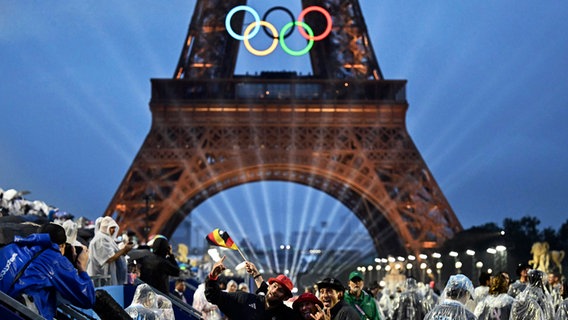 Der Eiffelturm und die Olympischen Ringe werden beleuchtet. © Loic Venance/Pool AFP/AP/dpa Foto: Loic Venance