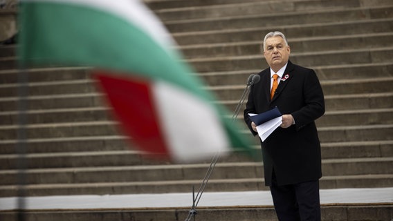 Der ungarische Ministerpräsident Viktor Orban steht neben einer ungarischen Flagge. © picture alliance / Anadolu | Stringer Foto: picture alliance / Anadolu | Stringer