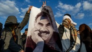 Jugendliche halten ein Plakat des inhaftierten Anführers der Arbeiterpartei Kurdistans (PKK), Öcalan, hoch. © dpa Foto: Metin Yoksu