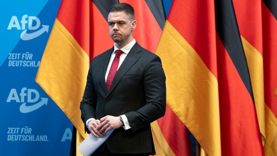 Hannes Gnauck, AfD Bundestagsabgeordneter und Vorsitzender der Jungen Alternative Deutschland (JA), steht auf dem AfD-Bundesparteitag auf der Bühne in Riesa (Sachsen). © dpa Foto: Sebastian Kahnert