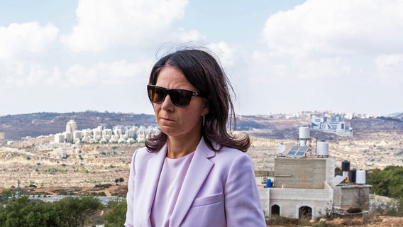 Bundesaußenministerin Annalena Baerbock (Bündnis 90/Die Grünen) ist auf einer Anhöhe, von der aus man im Hintergrund Häuser eines Vorortes von Ramallah und von israelischen Siedlern sehen kann. © dpa Foto: Soeren Stache