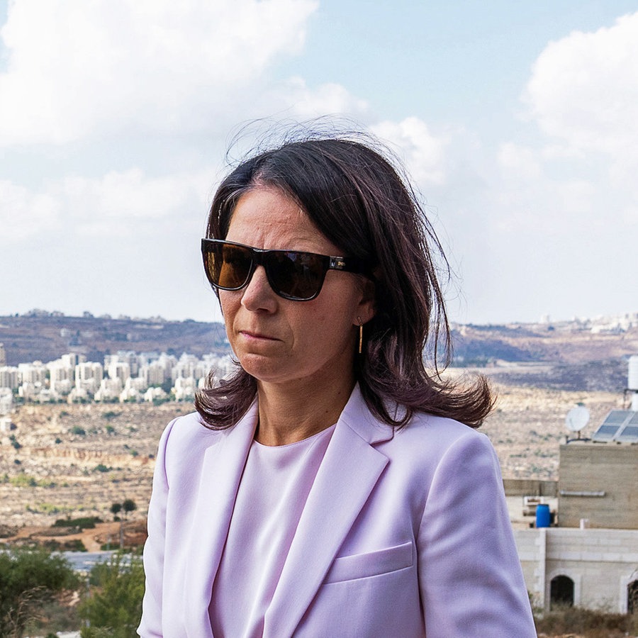 Bundesaußenministerin Annalena Baerbock (Bündnis 90/Die Grünen) ist auf einer Anhöhe, von der aus man im Hintergrund Häuser eines Vorortes von Ramallah und von israelischen Siedlern sehen kann. © dpa Foto: Soeren Stache