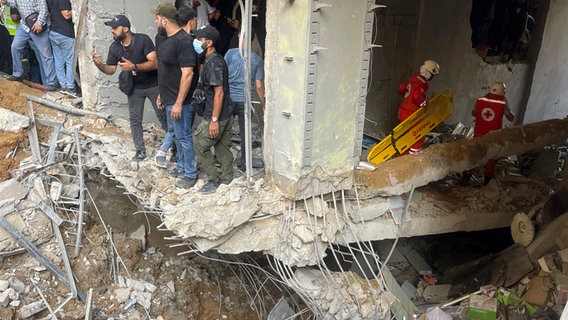 Menschen und Rettungskräfte versammeln sich am Ort eines israelischen Raketeneinschlags in den südlichen Vororten von Beirut (Libanon). © AP Foto: Bilal Hussein