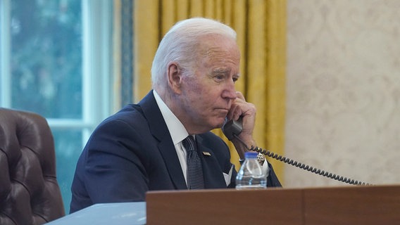 Auf diesem Bild, das durch ein Fenster aufgenommen wurde, telefoniert der Präsident der USA, Joe Biden, im Oval Office des Weißen Hauses. © AP/dpa Foto: Susan Walsh