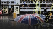 Eine Person geht mit einem Regenschirm mit Motiv britischer Flagge durch ein regnerisches London. © Imago Images Foto: Joerg Boethling