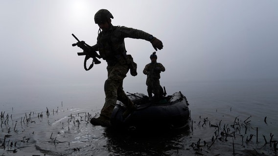 Ein ukrainischer Soldat springt am Ufer des Dnipro-Flusses an der Frontlinie nahe Cherson aus dem Boot. © AP/dpa Foto: Mstyslav Chernov