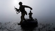 Ein ukrainischer Soldat springt am Ufer des Dnipro-Flusses an der Frontlinie nahe Cherson aus dem Boot. © AP/dpa Foto: Mstyslav Chernov