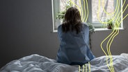 Einsame Frau sitzt allein auf dem Bett zu Hause. © Imago 