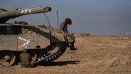 Ein israelischer Soldat sitzt auf einem Panzer und schaut auf ein Smartphone, nach Inkrafttreten einer vorübergehenden Feuerpause zwischen Israel und der islamistischen Hamas. © picture alliance/dpa/AP Foto: Tsafrir Abayov