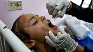 Ein Mitarbeiter des Gesundheitswesens verabreicht einem Kind in einem Krankenhaus eine Polio-Impfung. © AP/dpa Foto: Abdel Kareem Hana