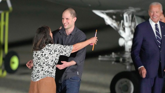 Der Reporter Evan Gershkovich umarmt seine Mutter Ella Milman, während US-Präsident Joe Biden zuschaut auf dem Luftwaffenstützpunkt Andrews nach dessen Freilassung im Rahmen eines Gefangenenaustauschs. Russland und der Westen machen einen beispiellosen Gefangenen-Deal. Foto:  +++ dpa-Bildfunk +++ © AP/dpa Foto: Manuel Balce Ceneta