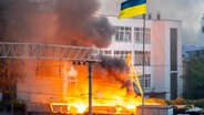 Die ukrainische Flagge ist vor dem Rauch eines Feuers zu sehen, nach russischen Angriffen auf Kiew. © ZUMA Press Wire/dpa Foto: Andreas Stroh