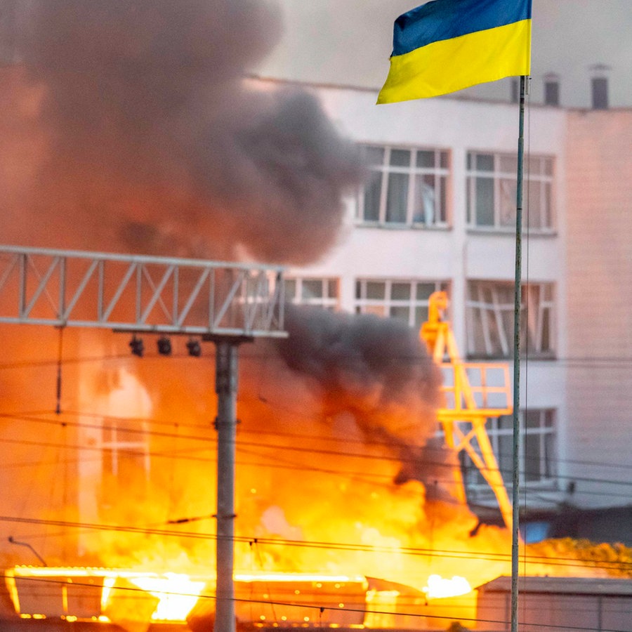 Die ukrainische Flagge ist vor dem Rauch eines Feuers zu sehen, nach russischen Angriffen auf Kiew. © ZUMA Press Wire/dpa Foto: Andreas Stroh