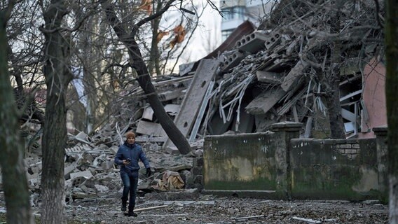 Ein Mann geht an einem Schulgebäude in Kramatorsk (Ukraine) vorbei, das bei einem Angriff schwer beschädigt wurde. © Libkos/AP/dpa Foto: Libkos