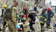 Auf diesem von der Nationalen Polizei der Ukraine zur Verfügung gestellten Foto arbeiten Rettungskräfte in der Nähe des durch einen Angriff zerstörten Restaurants RIA Pizza. © National Police of Ukraine/AP/dpa 
