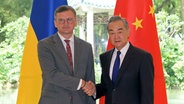 Der chinesische Außenminister Wang Yi (rechts) gibt dem ukrainischen Außenminister Dmytro Kuleba (links) bei einem Treffen in Guangzhou (China) die Hand. © XinHua/dpa Foto: Lu Hanxin