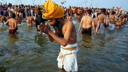 Ein Sadhu oder heiliger Hindu betet, bevor er ein heiliges Bad im Sangam nimmt, dem Zusammenfluss von Ganges, Yamuna und dem mythischen Saraswati, am "Mauni Amavasya" oder Neumondtag während des Maha Kumbh Festivals in Prayagraj (Indien). © AP/dpa Foto: Deepak Sharma