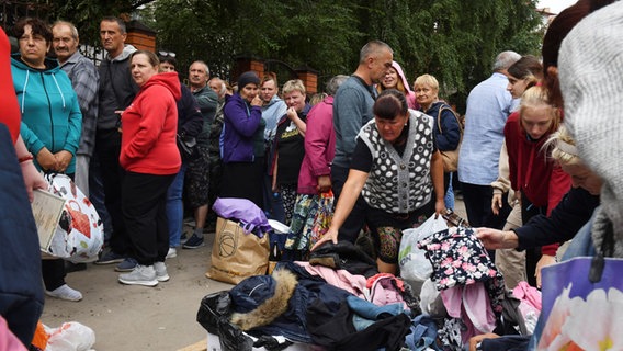 Menschen, die vor den Kämpfen zwischen russischen und ukrainischen Streitkräften evakuiert wurden, warten in einem Verteilungszentrum auf humanitäre Hilfe. © picture alliance/dpa/AP | Uncredited 