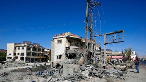 Ein Journalist, der eine Weste mit der Aufschrift "press" trägt, dokumentiert beschädigte Gebäude am Ort eines israelischen Luftangriffs im Dorf Temnin, Bekaa-Tal, Ostlibanon. © AP/dpa Foto: Hassan Ammar